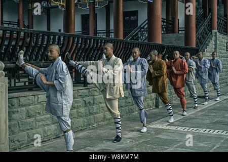 Chinesische Mönche dehnen ihre Beine, wie Sie üben Kung Fu und Martial Arts am westlichen Shaolin Tempel in Baihe Dorf, Stadt Zhongshan, Chongqing, C Stockfoto