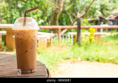 Eiskaffee im Glas auf dem Tisch Hintergrund Gras und Baum. Stockfoto