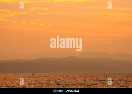 Goldenen Licht der Sonnenaufgang hinter den Bergen im Meer und Schatten Fischerboote. Stockfoto