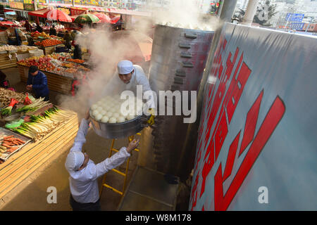 Chinesische Arbeiter heben gedämpfte Brötchen aus einem 4 Meter hohen Dampfgarer in einem Markt, in Qingdao, Provinz Shandong, China, 30. Januar 2016. Mantou, Stockfoto