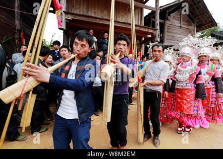 Chinesische Männer schlag Rohrflöten und traditionell gekleidete Frauen der ethnischen Minderheit Miao Tanz zu feiern das chinesische Mondjahr, auch bekannt als Spri Stockfoto
