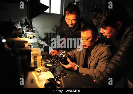 Chinesische Reparatur veteran Zhan Chunming, Mitte, beauftragt seine Lehrlinge ein Objektiv in seinem Geschäft in Peking, China zu reparieren, 10. Januar 2016. Zhan Chunmi Stockfoto