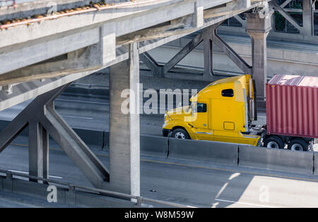 Big Rig leistungsstarke Gelb Long Haul Industrial Grade Semi Truck Transport kommerzielle Güter im Container auf Flachbett Auflieger bewegen auf dem Teilen Stockfoto