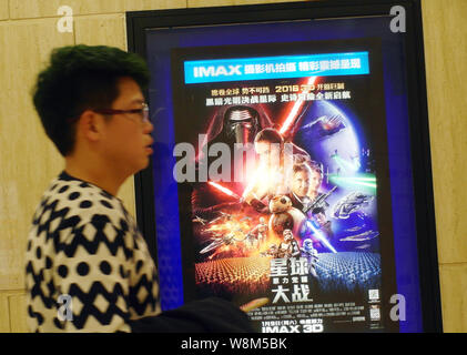 ---- Eine Chinesische filmgoer Spaziergänge hinter einem Plakat des Films Star Wars: Die Kraft, die erwacht" in einem Kino in der Stadt Yichang, Provinz Hubei in Zentralchina Stockfoto