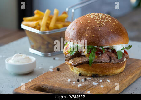 Highigh Burger mit Pommes frites in small fry Warenkorb auf Betonflächen. Traditionelle amerikanische Fastfood. Stockfoto