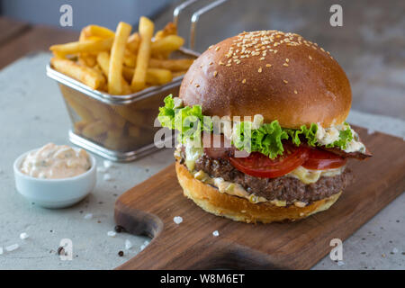 Highigh Burger mit Pommes frites in small fry Warenkorb auf Betonflächen. Traditionelle amerikanische Fastfood. Stockfoto