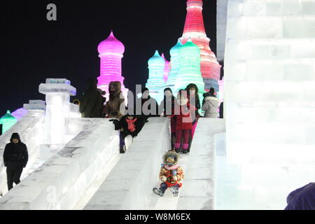 Touristen genießen. Objektträger auf Eis Gleitbahnen während der 32 Harbin International Eis und Schnee Festival in der Stadt Harbin, im Nordosten Chinas Heilongjiang provi Stockfoto