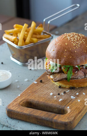 Highigh Burger mit Pommes frites in small fry Warenkorb auf Betonflächen. Traditionelle amerikanische Fastfood. Stockfoto