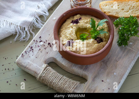 Eine Nahaufnahme eines bunten snack Zusammensetzung auf einer hölzernen Hintergrund. Köstliche hummus in Glasschale und auf einer Holzplatte. Stockfoto