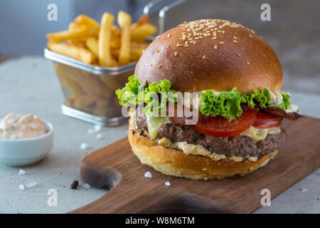 Highigh Burger mit Pommes frites in small fry Warenkorb auf Betonflächen. Traditionelle amerikanische Fastfood. Stockfoto