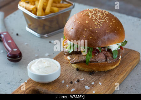 Highigh Burger mit Pommes frites in small fry Warenkorb auf Betonflächen. Traditionelle amerikanische Fastfood. Stockfoto