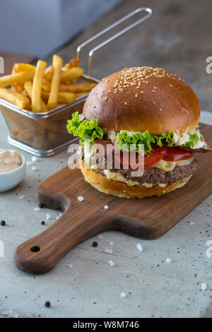 Highigh Burger mit Pommes frites in small fry Warenkorb auf Betonflächen. Traditionelle amerikanische Fastfood. Stockfoto