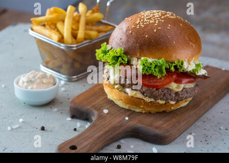 Highigh Burger mit Pommes frites in small fry Warenkorb auf Betonflächen. Traditionelle amerikanische Fastfood. Stockfoto