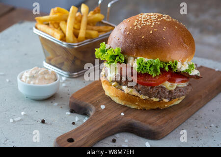 Highigh Burger mit Pommes frites in small fry Warenkorb auf Betonflächen. Traditionelle amerikanische Fastfood. Stockfoto