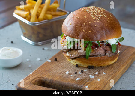 Highigh Burger mit Pommes frites in small fry Warenkorb auf Betonflächen. Traditionelle amerikanische Fastfood. Stockfoto