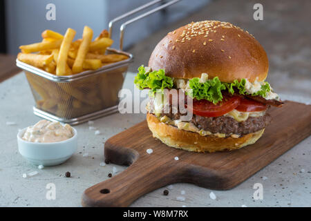 Highigh Burger mit Pommes frites in small fry Warenkorb auf Betonflächen. Traditionelle amerikanische Fastfood. Stockfoto