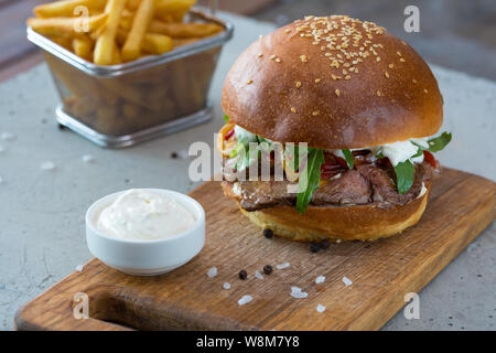 Highigh Burger mit Pommes frites in small fry Warenkorb auf Betonflächen. Traditionelle amerikanische Fastfood. Stockfoto