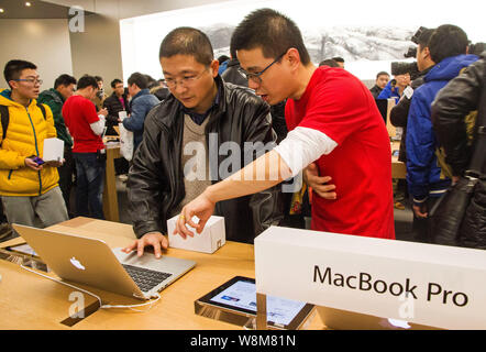 ---- Ein chinesischer Mitarbeiter, rechts in Rot, unterstützt einen Kunden ein MacBook Pro Laptop Computer im Apple Store an der MixC (Mix Stadt) sh zu versuchen Stockfoto