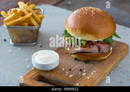 Highigh Burger mit Pommes frites in small fry Warenkorb auf Betonflächen. Traditionelle amerikanische Fastfood. Stockfoto