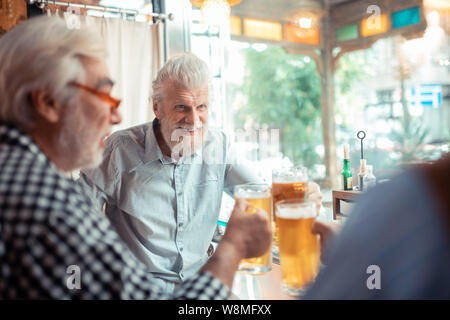 Mann lächelnd beim Trinken von Bier mit Freunden Stockfoto