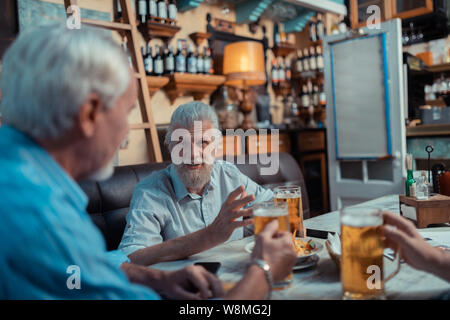 Grau bärtigen Haaren reifer Mann sprechen mit Freunden Stockfoto