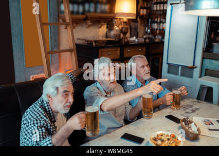 Drei Rentner Fußball in der Kneipe beobachten Stockfoto