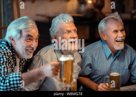 Drei Rentner lachen während Fußball in Pub beobachten Stockfoto