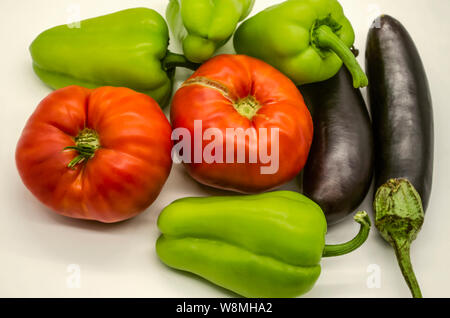 Ernte Sommer Gemüse, große, rote Tomaten, grüne Paprika und Schwarz und violett Auberginen in Armenien gewachsen liegen auf einem weißen Hintergrund Stockfoto