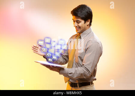 Geschäftsmann mit einem digitalen Tablet und von ihm emittierende Symbole Stockfoto