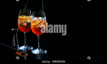 Aperol Stpritz Cocktail mit Eiswürfel und Orangenscheiben auf schwarzen Hintergrund. Klassische italienische Aperitif trinken mit Cocktail Zubehör Stockfoto