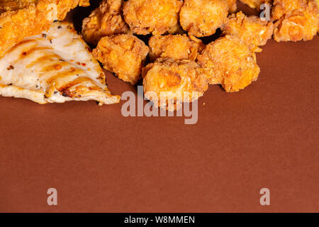 Knusprig gebratene Hähnchen und Pommes Frites gegen braunen Hintergrund Stockfoto