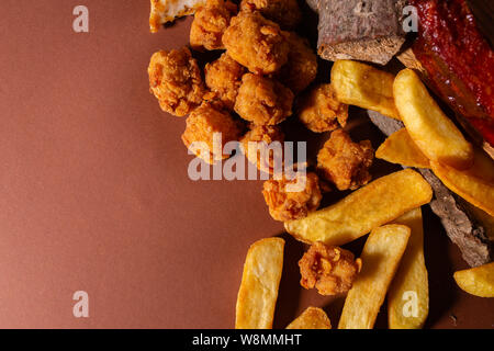 Knusprig gebratene Hähnchen und Pommes Frites gegen braunen Hintergrund Stockfoto