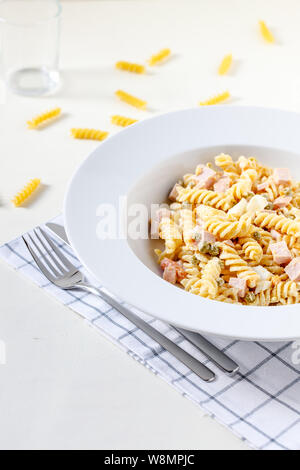 Nudelsalat mit Messer und Gabel auf weißen Tisch Stockfoto