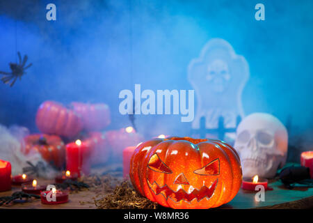 Scary Pumpkin für Halloween durch Nebel auf einer hölzernen Tisch umgeben. Brennende Kerzen. Stockfoto
