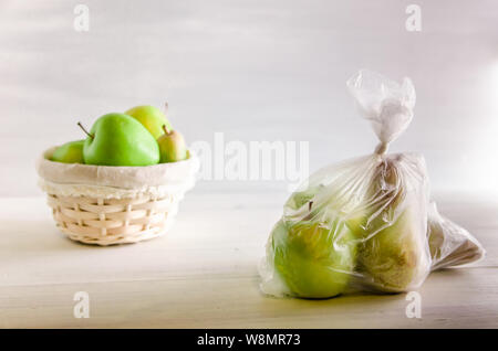 Concept Kunststoff kostenloses Obst in eine Plastiktüte und Weidenkorb auf weißem Hintergrund Stockfoto