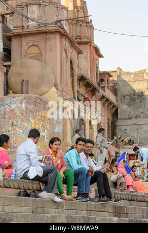 Indische Leute sitzen der Schritte eines Ghat mit Blick auf den Fluss Ganges in Varanasi, Uttar Pradesh, Indien, Südasien. Auch als Benares bekannt, Stockfoto