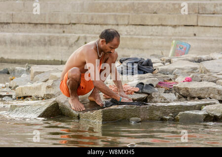 Ein Inder wäscht seine Kleider im Fluss Ganges in Varanasi, Uttar Pradesh, Indien, Südasien. Auch als Benares, Banaras und Kashi bekannt. Stockfoto