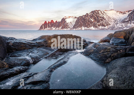 Blick über die bunten Felsen und Felsenpools, schneebedeckten Bergen, Tungeneset Oksen Teufel kiefer Senja Norwegen Stockfoto