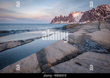 Blick über die bunten Felsen und Felsenpools, schneebedeckten Bergen, Tungeneset Oksen Teufel Kiefer Senja Norwegen Stockfoto