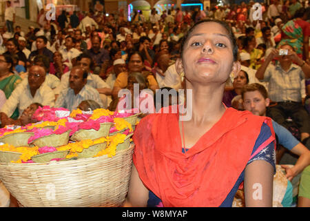 Blume Kerze Verkäufer unter Pilgern und Touristen beobachten die nächtliche Hindu Ganga Aarti Zeremonie an Dashashwamedh Ghat in Varanasi, Indien Stockfoto