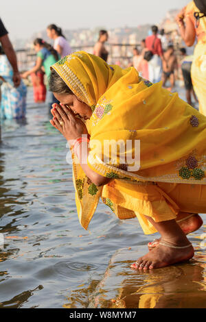 Ein indisch-hinduistischen Frau trägt einen gelben Sari bietet Gebete an die Götter an den Ufern des Flusses Ganges in Varanasi, Uttar Pradesh, Indien, Südasien Stockfoto