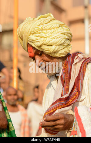 Eine alte indische Sikh Mann mit einem Gelben Turbane Spaziergänge unter den Pilgern in Varanasi, Uttar Pradesh, Indien, Südasien. Auch als Benares bekannt Stockfoto