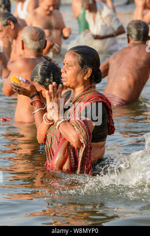 Ein indisch-hinduistischen Frau im Sari bietet Gebete an die Götter während am frühen Morgen Baden Ritual in den Fluss Ganges in Varanasi, Indien Stockfoto