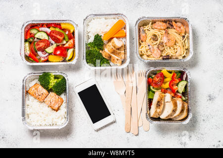 Lebensmittel-lieferservice. Verschiedene Behälter aus Aluminium mit gesunde Ernährung natürliche Nahrung. Ansicht von oben auf weißem Hintergrund. Stockfoto