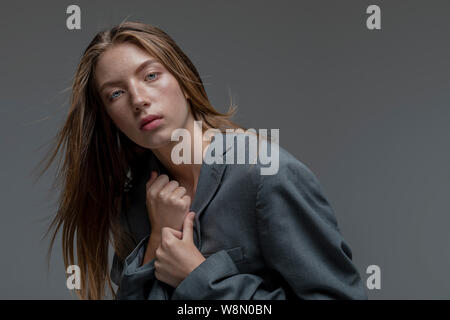 Porträt der jungen Modell in Lose graue Jacke isoliert grauer Hintergrund Stockfoto
