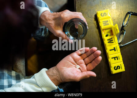 Ältere Frau nehmen Pillen aus. Gesundheit und Alter Konzept mit Arzneimitteln. Medikamente auf dem Tisch. Stockfoto