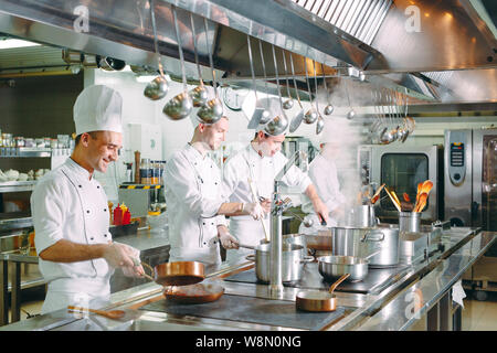 Moderne Küche. Köche bereiten Mahlzeiten auf dem Herd in der Küche des Restaurant oder Hotel. Das Feuer in der Küche. Stockfoto