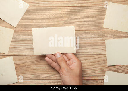 Altes Foto in den Händen des Menschen. Leere Vorlage für Bild, Mock-up. Holz- Hintergrund Stockfoto