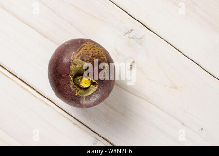 Ein ganzes deep purple Mangosteen copyspace auf der rechten flatlay auf weißem Holz Stockfoto