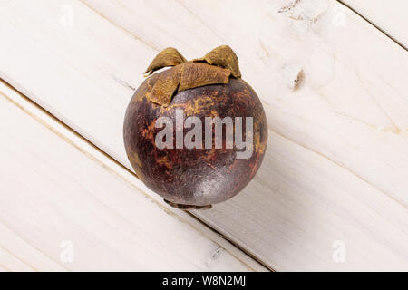 Ein ganzes deep purple Mangosteen flatlay auf weißem Holz Stockfoto